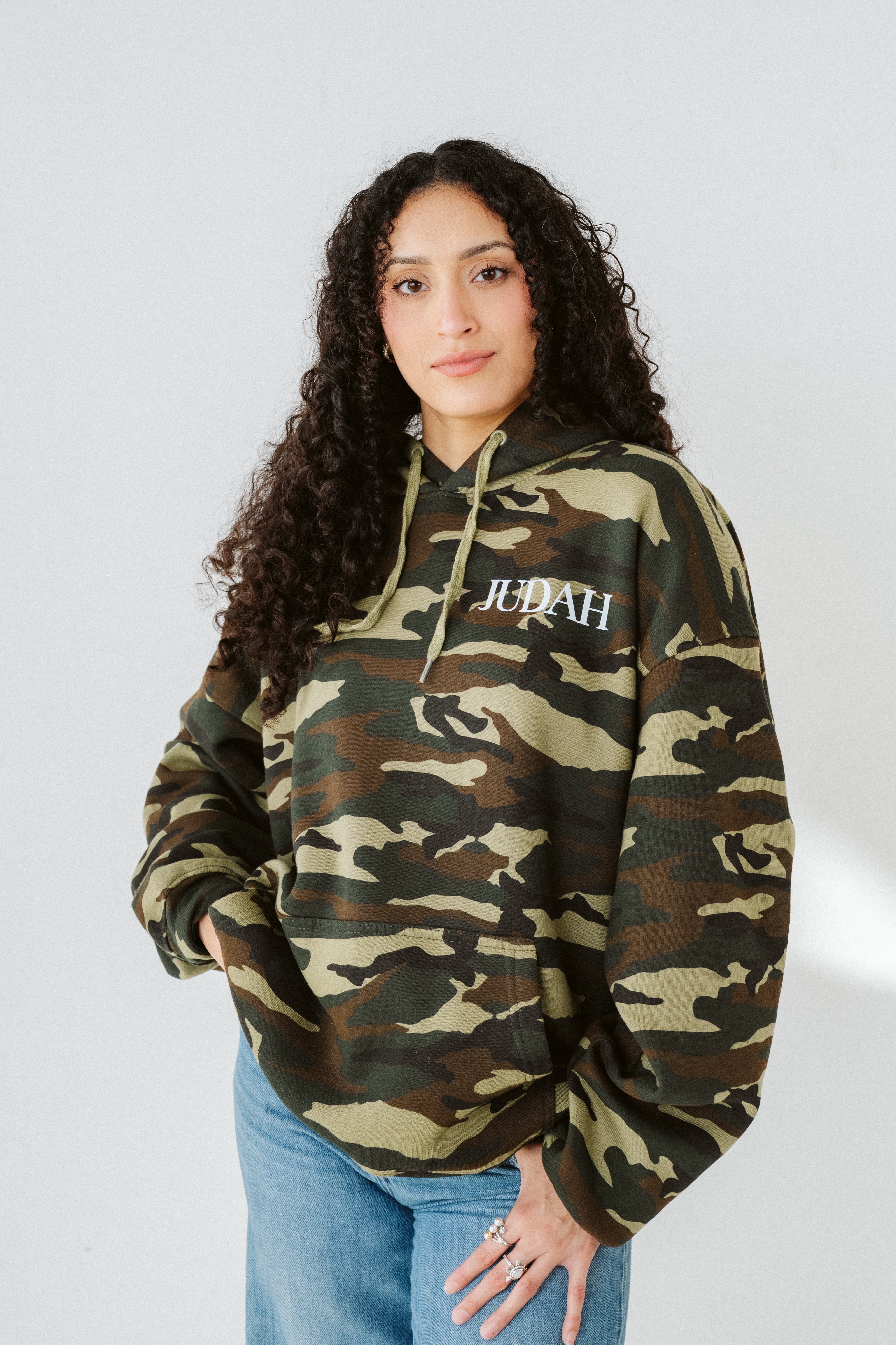Person wearing a camouflage hoodie with 'Jubah' branding on a white background