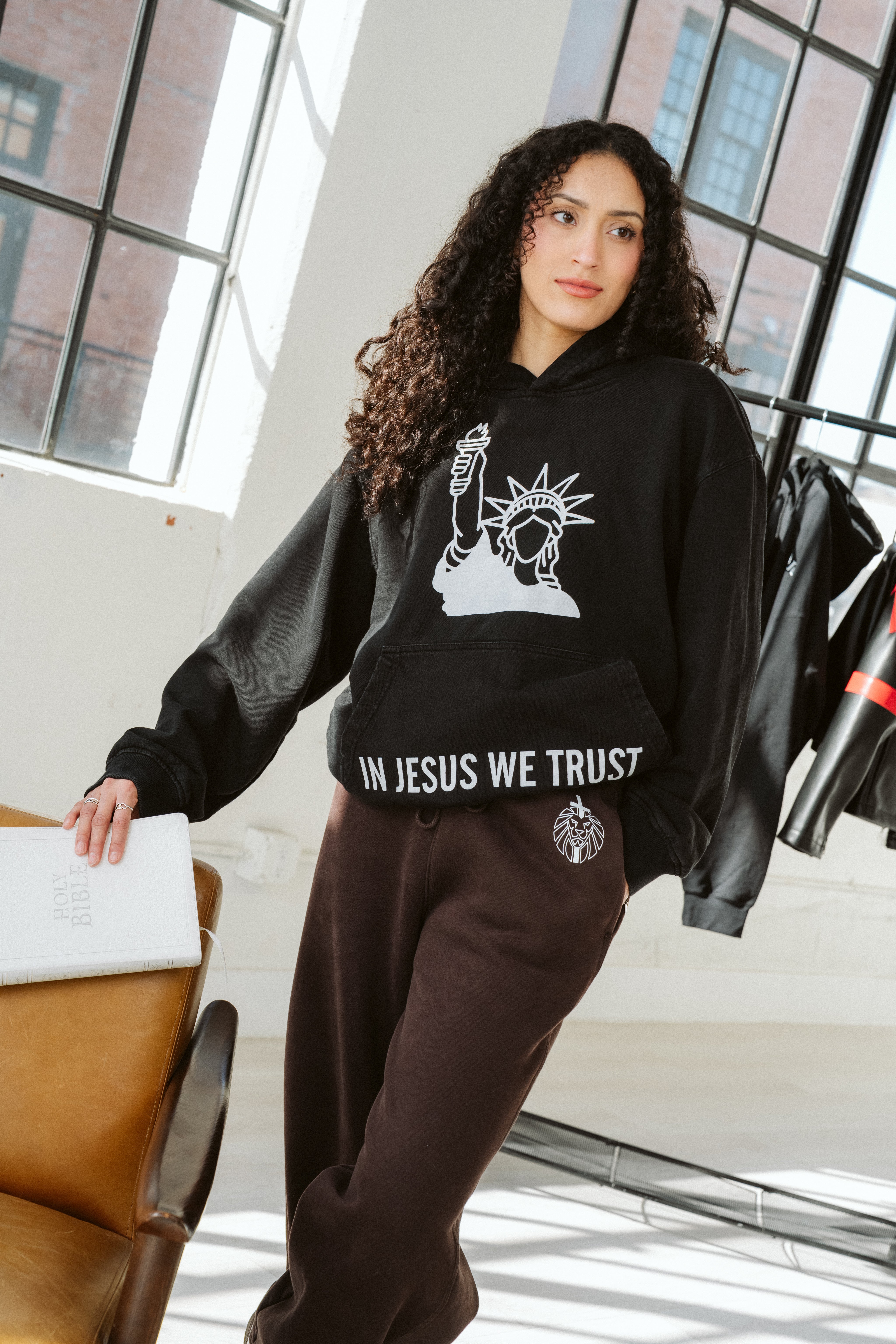 Person wearing a black hoodie with a graphic design in a modern indoor setting